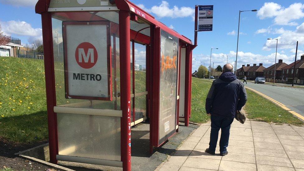 William Thomas stands next to a bus stop