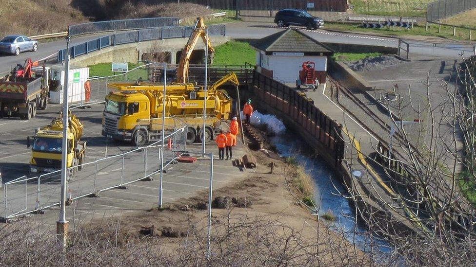 Workers next to stream