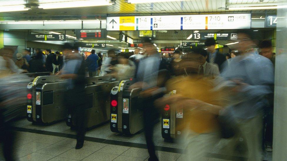 Blurred photo of travellers walking through ticket machines