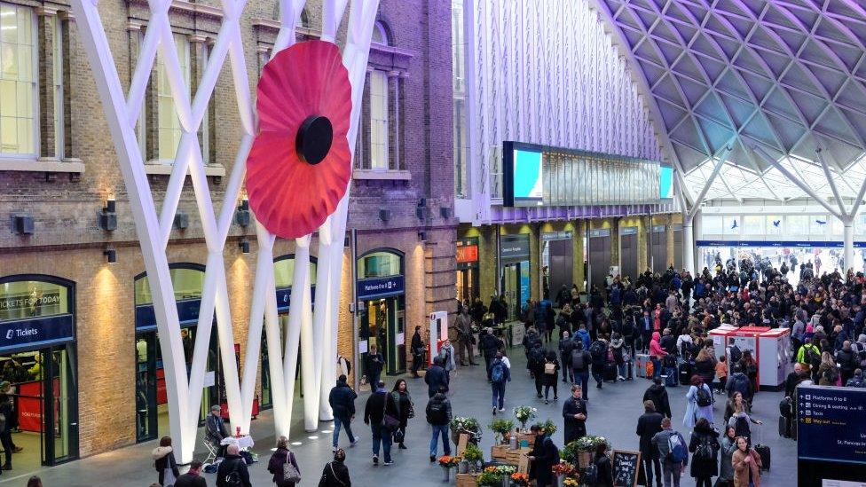 A giant red poppy hangs in the atrium on the concourse at King's Cross station