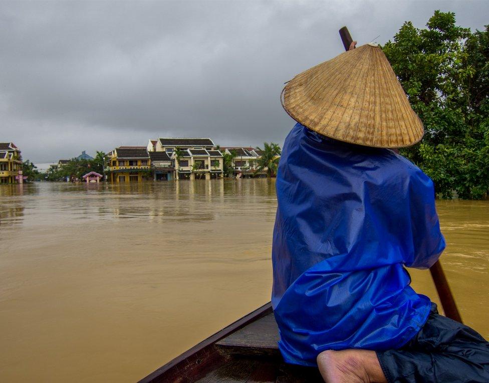 A man paddles through the flooded streets of Hoi An, Vietnam