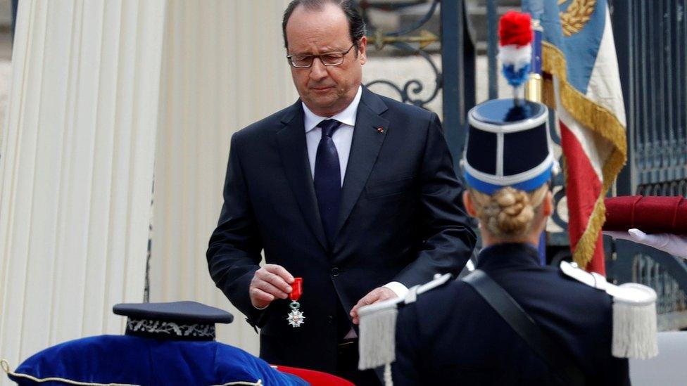 French President Francois Hollande awards posthumously the Legion d"Honneur to Jean-Baptiste Salvaing who was killed by an extremist pledging allegiance to the Islamic State group, during a memorial ceremony in Versailles, near Paris, on June 17, 2016.