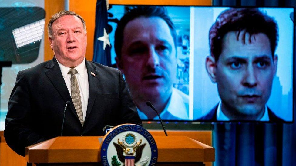 Michael Spavor and Michael Kovrig are shown on a video monitor as US Secretary of State Mike Pompeo, speaks during a news conference in July