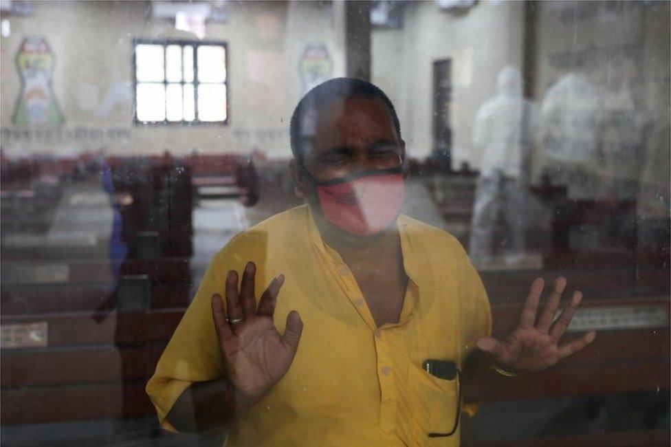 A relative leans against a glass window at the crematorium where a family member who died from the coronavirus disease (COVID-19) is prepared for cremation, in New Delhi, India, April 9, 2021.