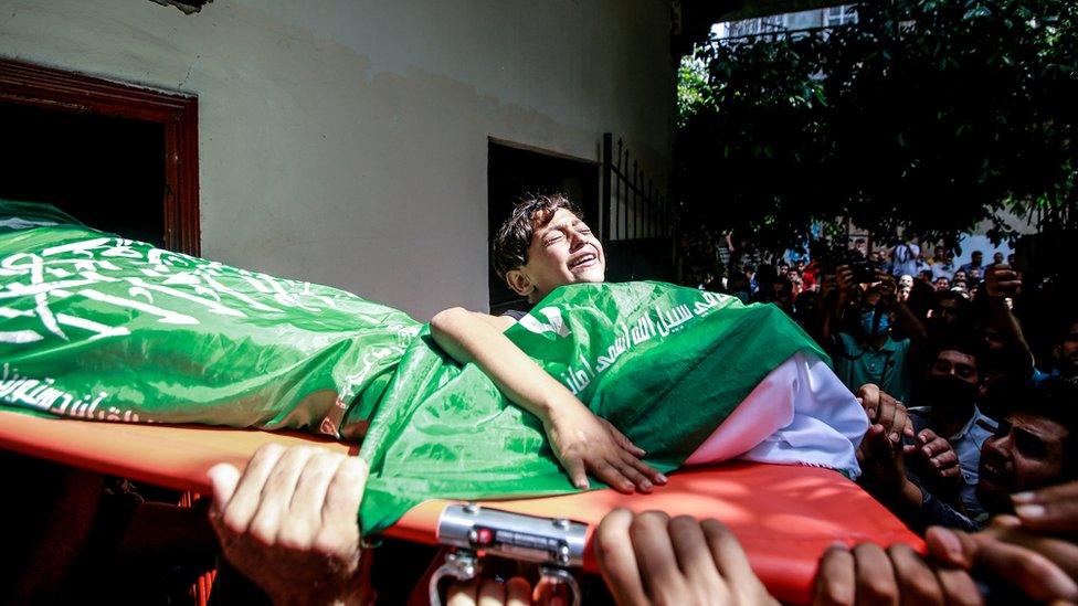 Palestinian boy holding stretcher during funeral