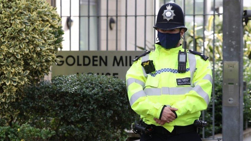 A police officer stands outside he block of flat where the bodies were found