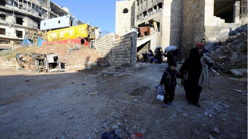 People, who evacuated the eastern districts of Aleppo, carry their belongings as they walk in a government held area of Aleppo, Syria on 9 December 2016.