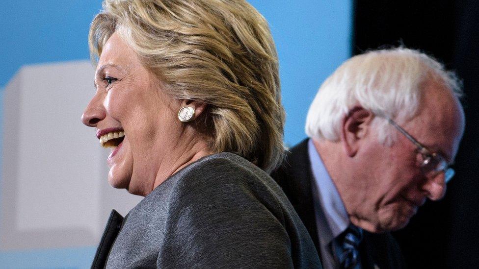 Hillary Clinton and Bernie Sanders face different directions at a 2016 campaign event.