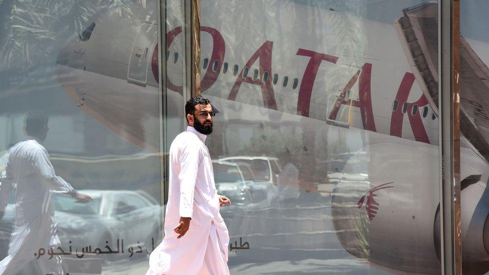 Man walks past Qatar Airways window display