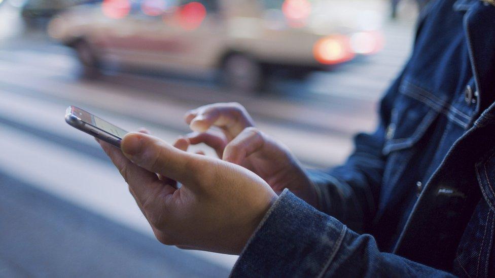 A man uses a mobile phone at Shibuya crossing - stock photo