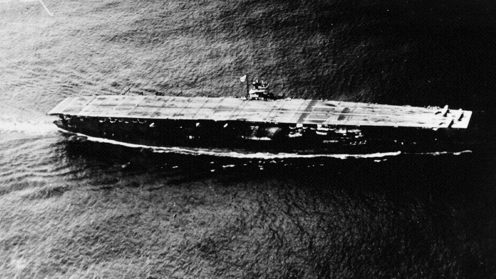 Black and white image shows the aircraft carrier on water