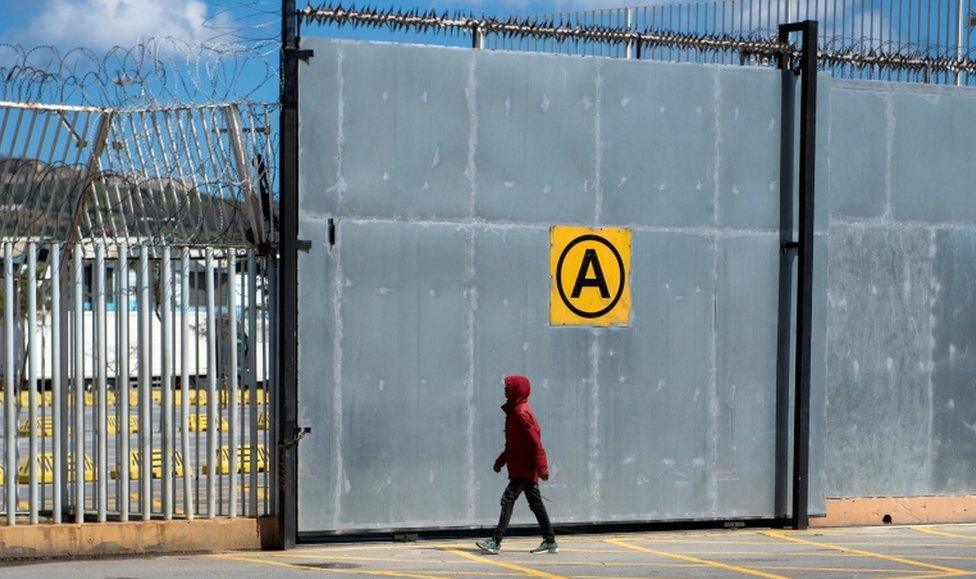 A young Moroccan walks toward a fence at the harbour of the port city of Ceuta