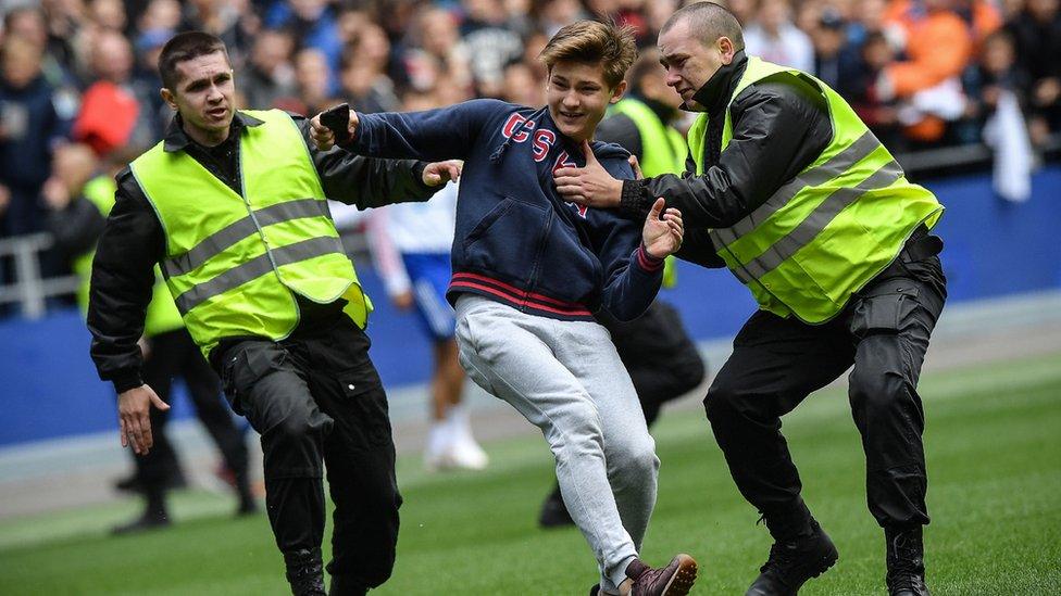 Security guards catch a pitch invader during a training session of the Russian national football team at Moscow's VEB Arena stadium on June 9, 2018