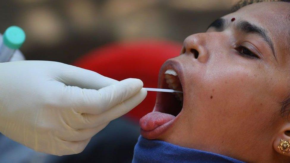 A doctor takes a swab sample of a resident at a Covid-19 coronavirus testing drive inside the Dharavi slums