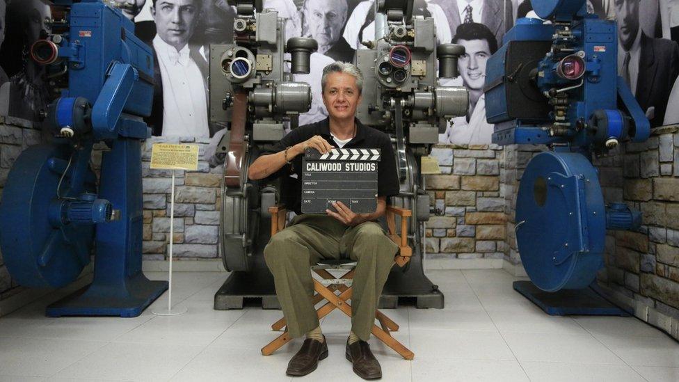 Santiago Cardenas poses with a sign at the Caliwood Museum