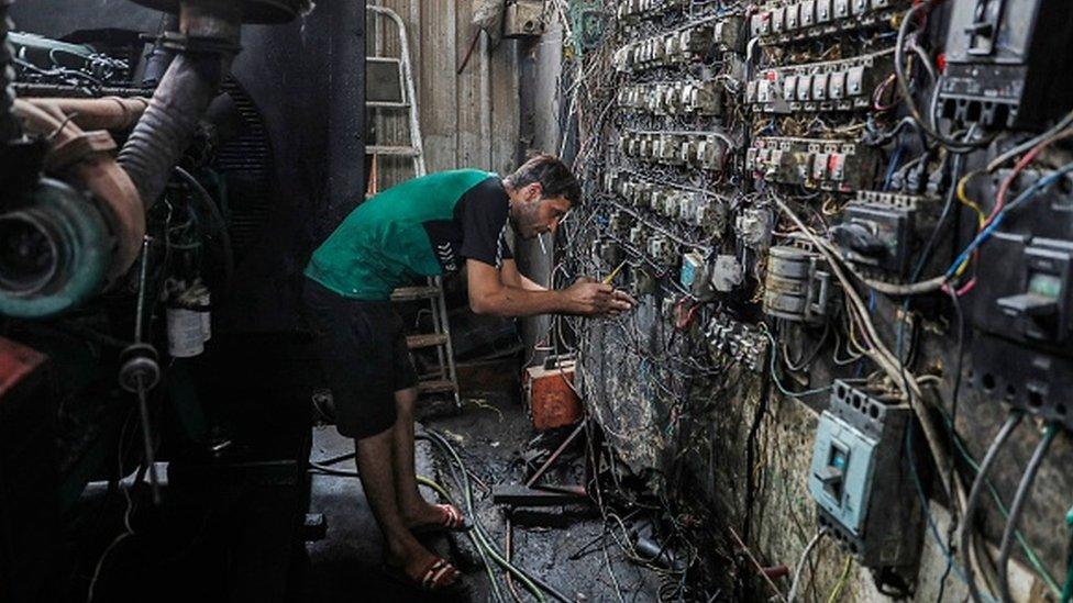 A technician controls an electric switch board connecting homes to privately owned electricity generators in a suburb of Iraq's capital Baghdad