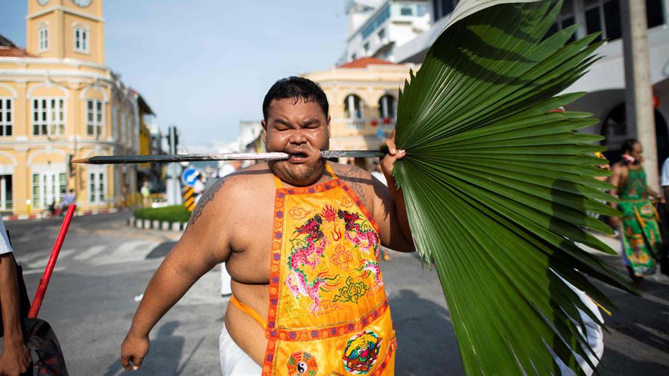 A devotee has a plum leave pierced through his cheek