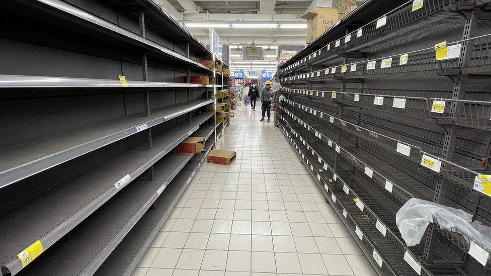 Stacks of empty shelves in a supermarket aisle in Puxi, Shanghai