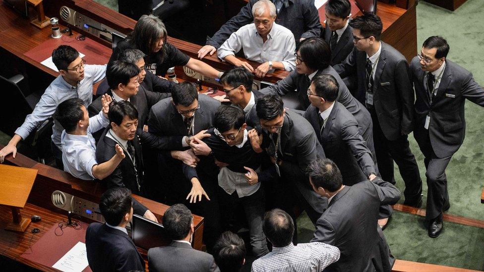 Newly elected lawmaker Sixtus Leung (C) is restrained by security after attempting to read out his Legislative Council oath at Legco in Hong Kong on November 2, 2016