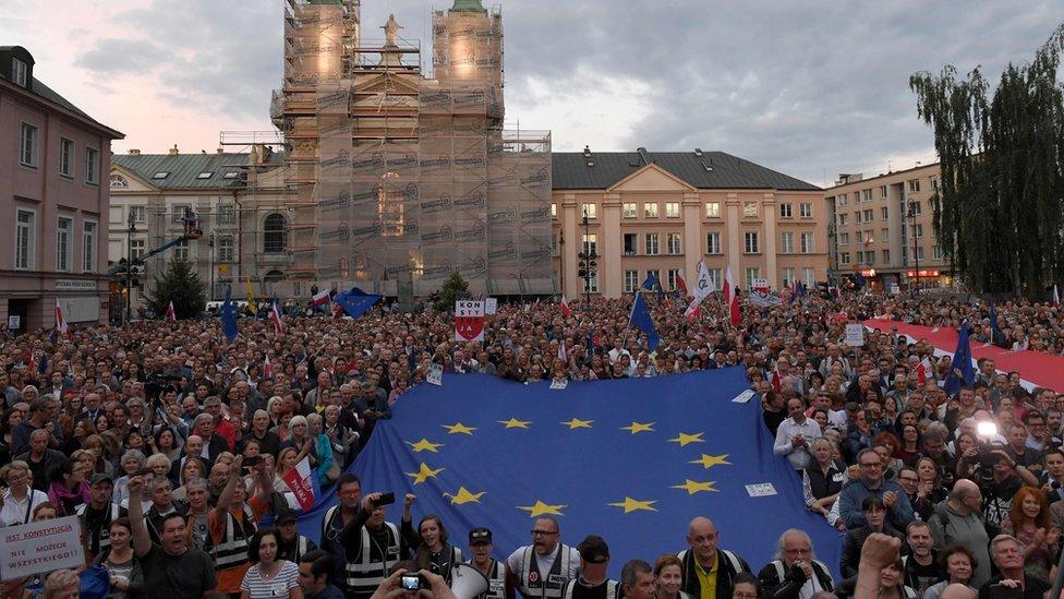 Protestors shout slogans and wave flags as they attend a demonstration in support of Supreme Court judges in front of The Supreme Court in Warsaw