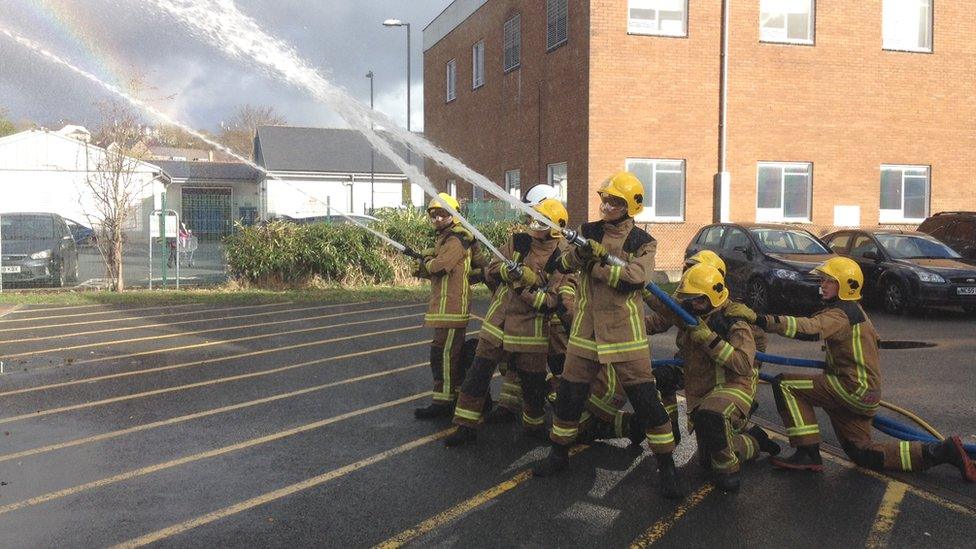 Young people train with a fire hose