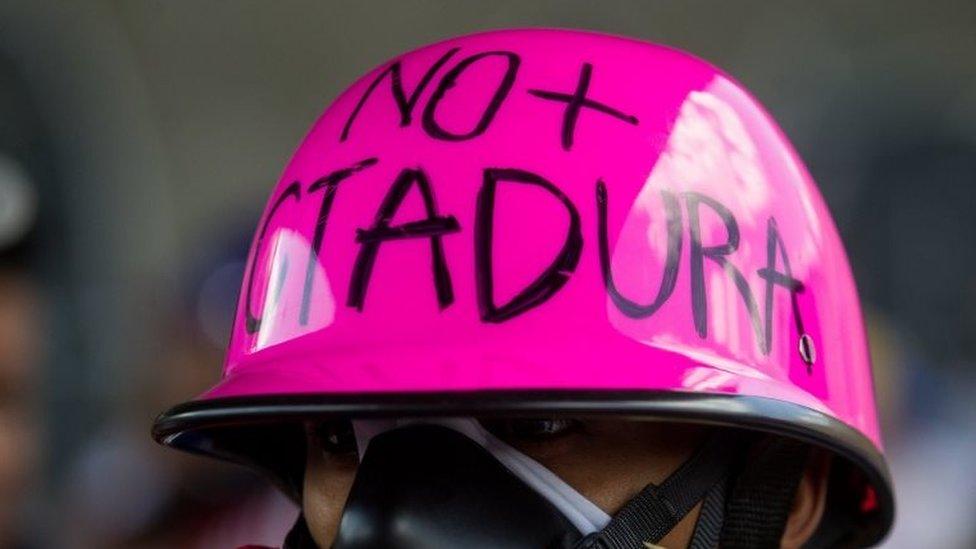 A man with a message in his helmet that reads "No dictatorship" participates in a demonstration in Caracas, Venezuela, 20 May 2017.