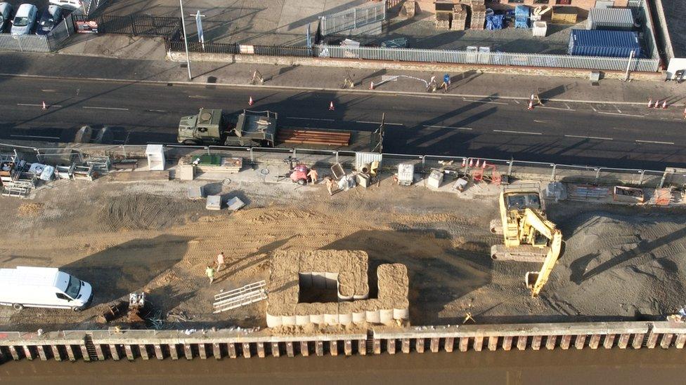 A crane lifting sandbags into position