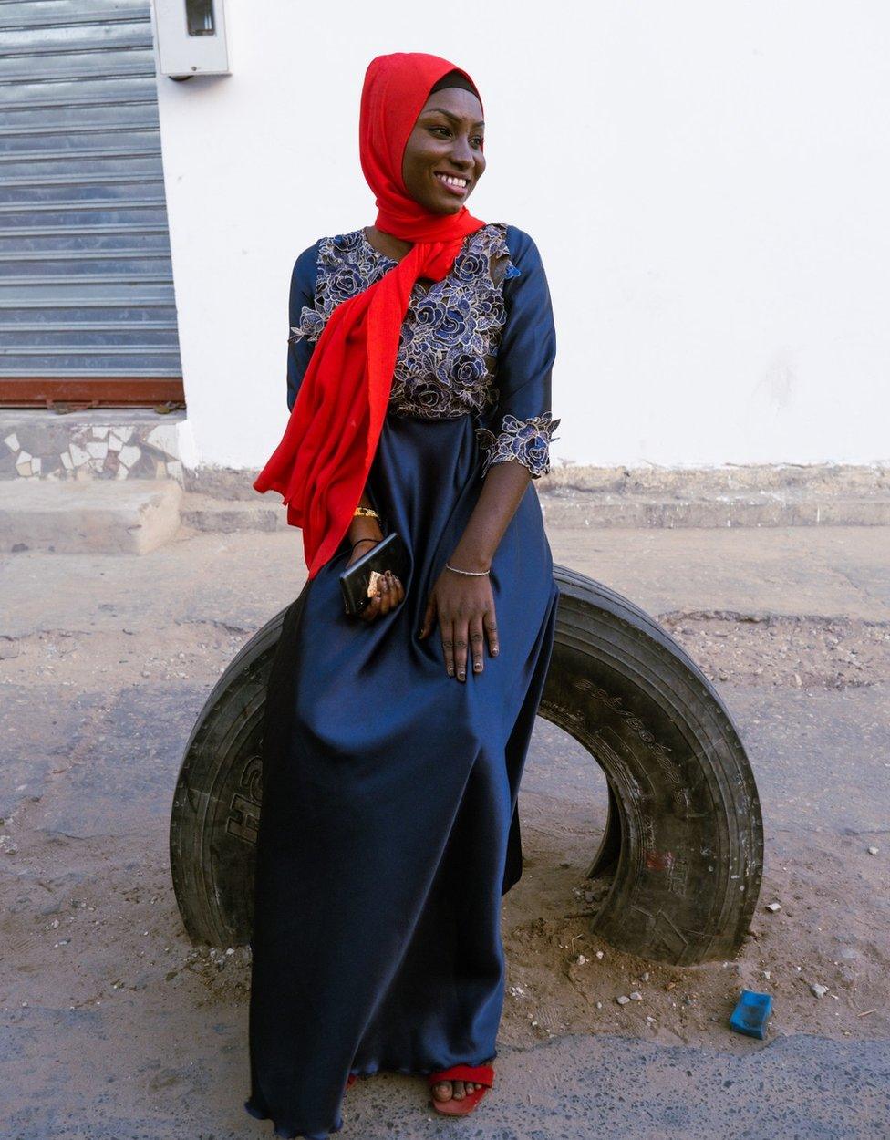 Dienaba Balde wears a blue outfit plus red accessories