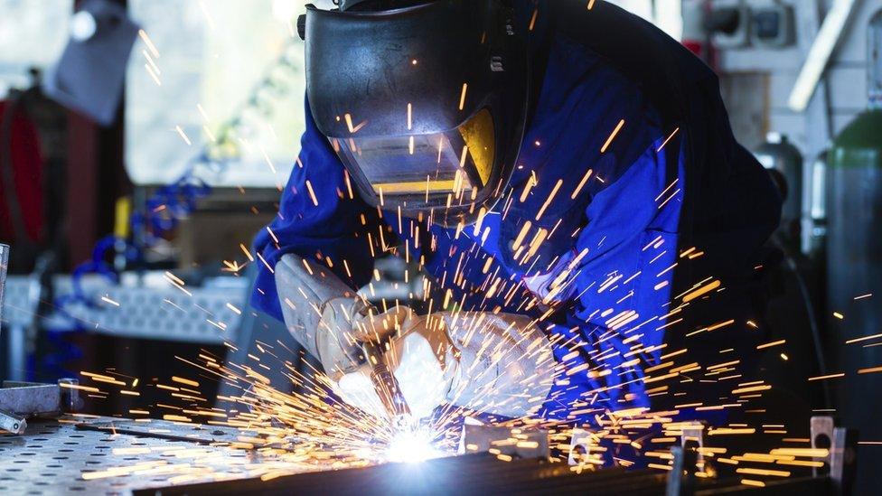 Worker welding metal in workshop with sparks