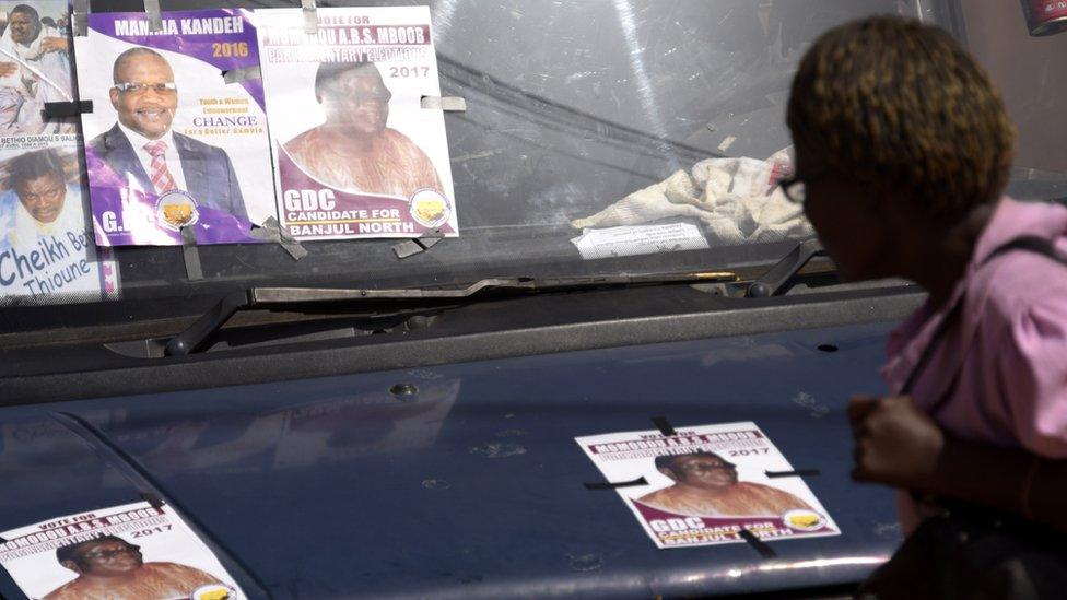 A woman looks at electoral posters displayed on a car