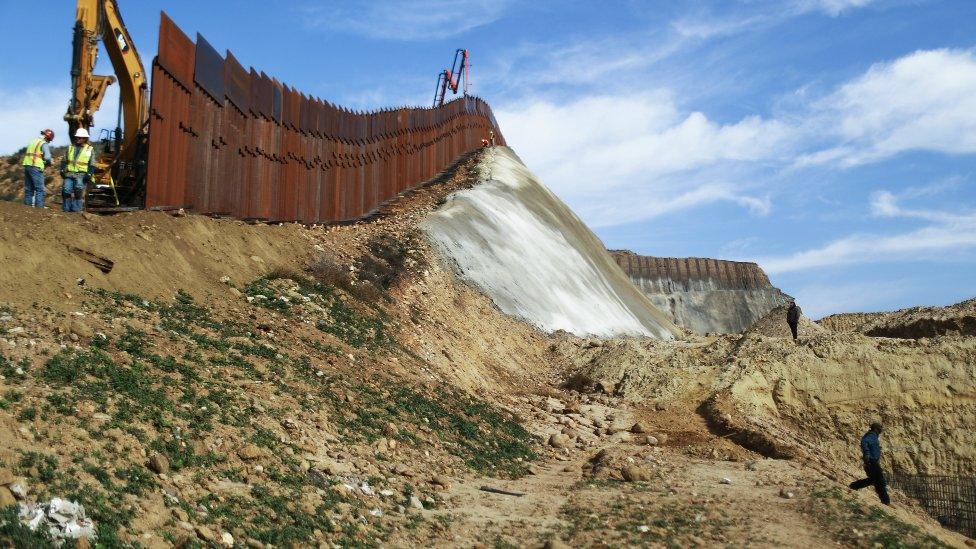 A construction crew works as new sections of the US-Mexico border barrier are installed on January 11, 2019 as seen from Tijuana, Mexico