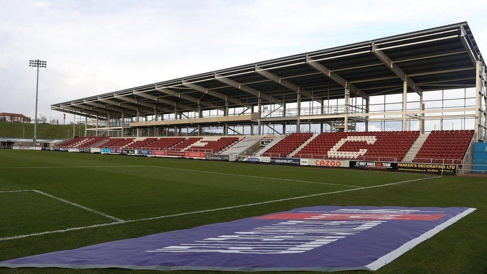 Covered stand alongside football pitch with "