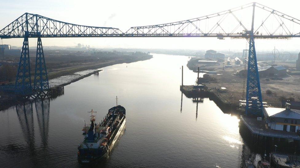 A dredger sails under the Transporter Bridge on the River Tees