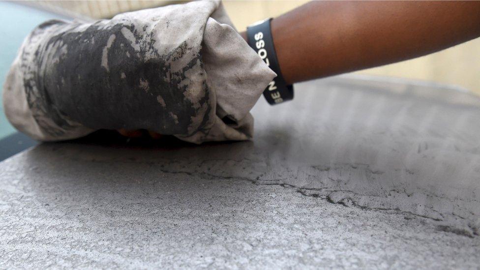 An attendant wipes clean black soot covering a car