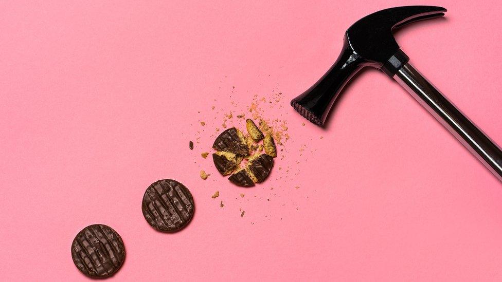 a line of 3 chocolate biscuits, one is smashed by a hammer