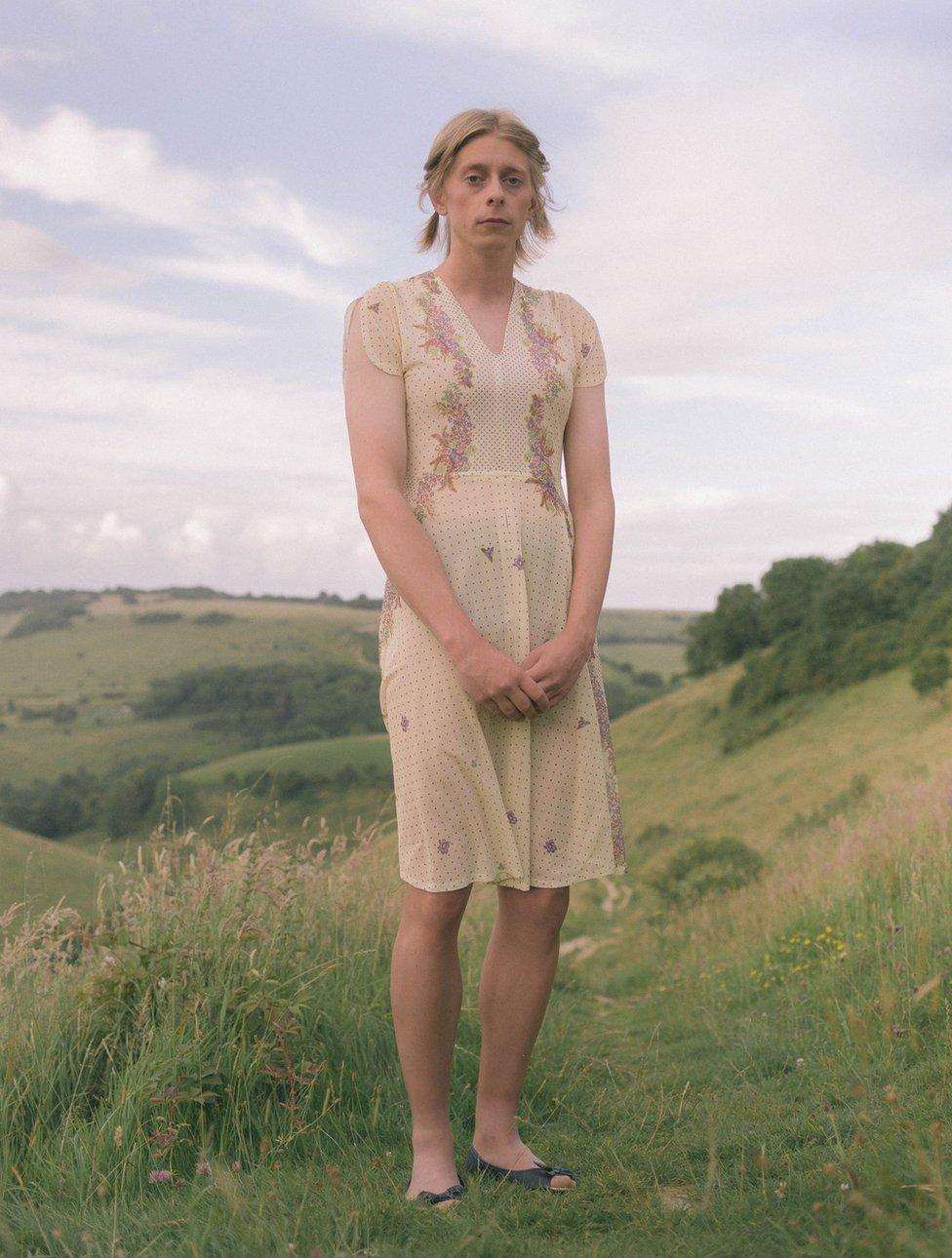 A person wearing a dress standing on a grassy hill