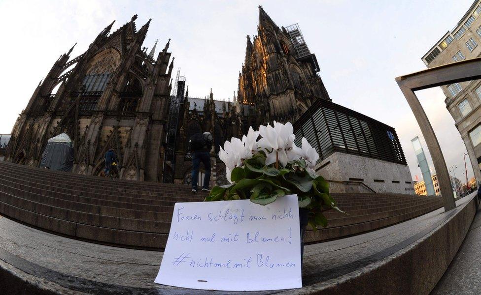 Flowers and a letter reading "One doesn't beat women - not even with flowers" are laid down in front of Cologne's Cathedral