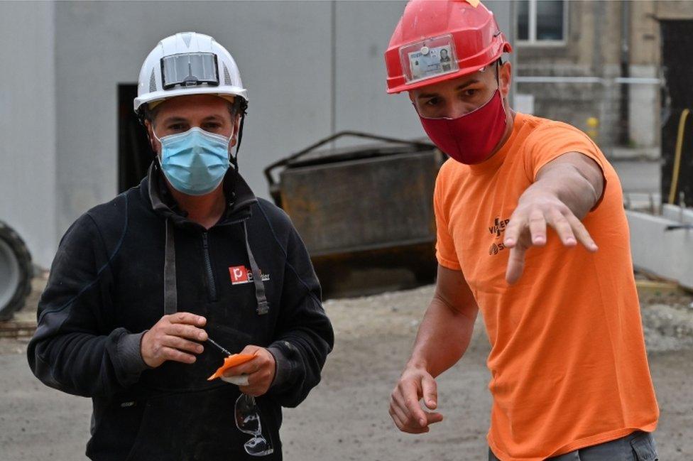 Construction workers wearing protective masks work on April 28, 2020, at a parking construction site in Chambery, eastern France