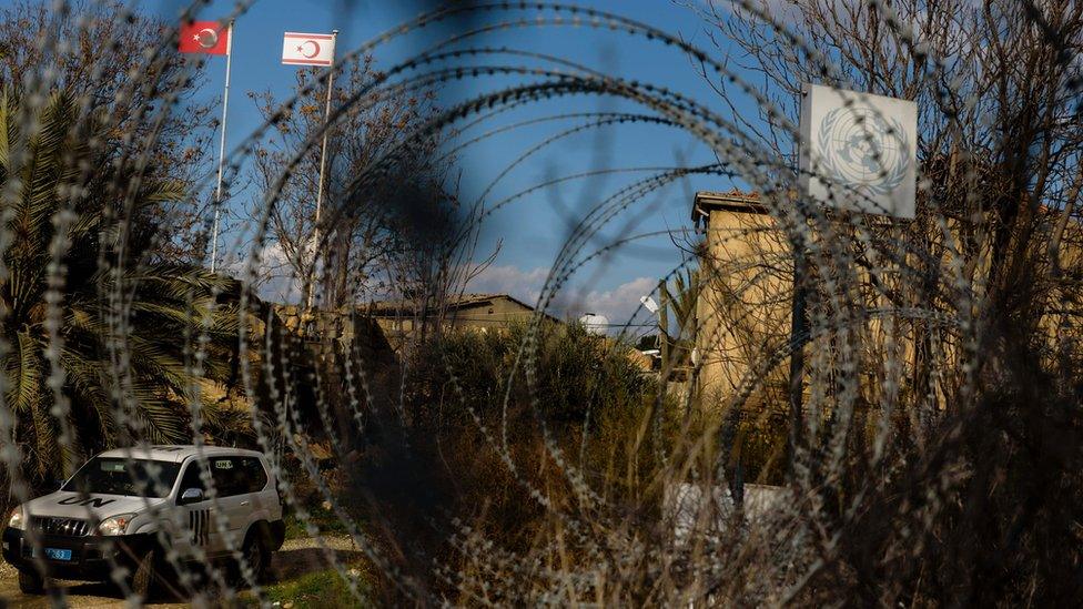 A UN vehicle drives past abandoned buildings in the green line, a UN controlled buffer zone, separating the divided Cypriot capital of Nicosia on January 4, 2017