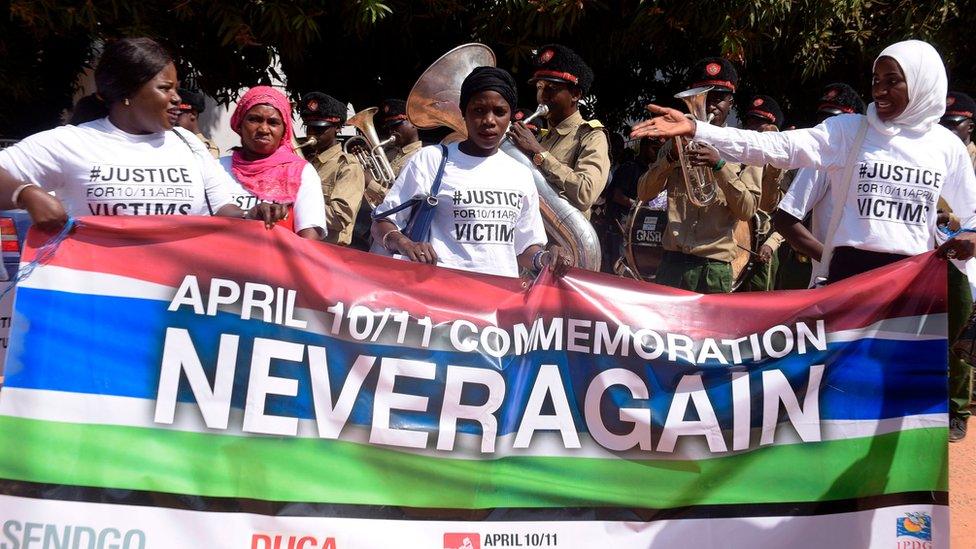 Demonstrators hold a banner reading "April 10/11 commemoration - Never Again" in rememberance of victims of the Gambia"s former regime, in Serekunda, The Gambia, on April 4, 2017