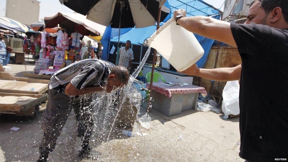 A man pours water on another man in Baghdad on 30 July, 2015