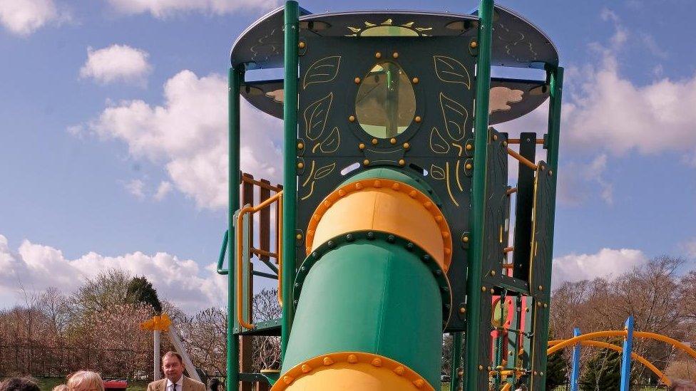 Green and yellow platform from which a green and yellow tube slide is emerging