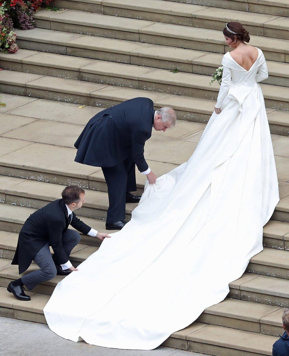 Princess Eugenie of York receives help with her train from her father Prince Andrew