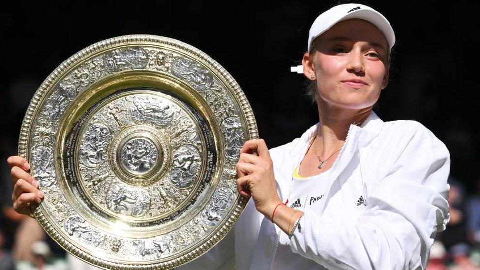 wimbledon's women's singles champion elena holds her trophy with a smile on her face