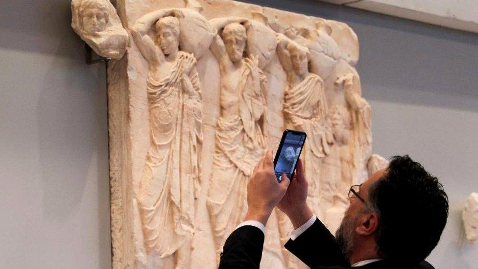 A visitor takes a photo of one of three Parthenon fragments, returned from the Vatican