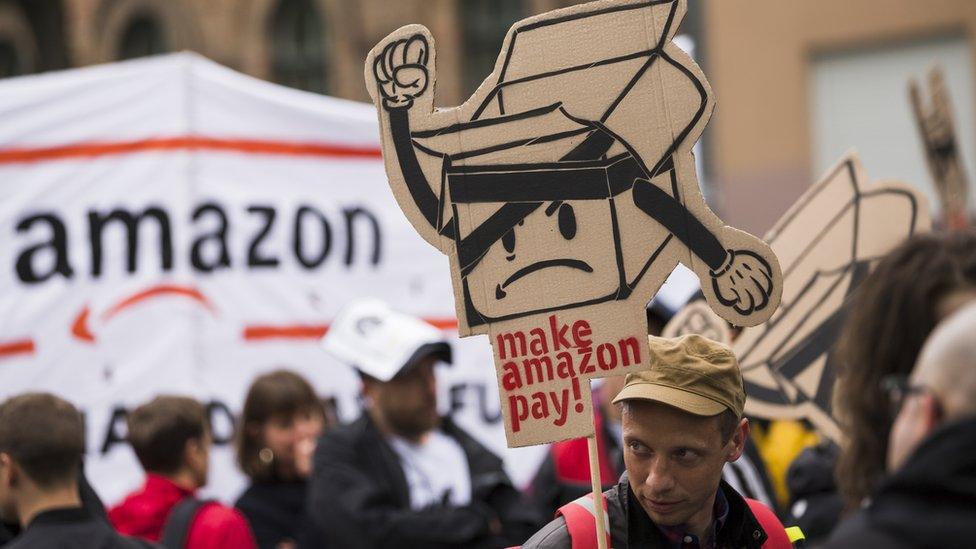 People hold banners during a demonstration attended from Amazon-Workers, trade union members and left activits under the motto 'Make Amazon Pay' in Berlin, Germany on April 24, 2018.