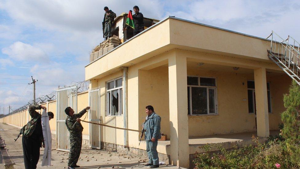 Afghan security forces replace the Taliban banner with the Afghan flag on a police post near Kunduz