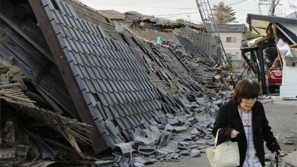 A resident walks past collapsed houses in Mashiki, Kumamoto prefecture, southern Japan, Friday, April 15, 2016,