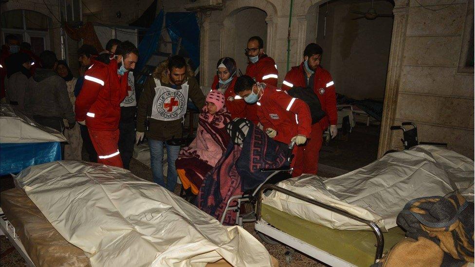 Girl in a wheelchair, being pushed away by Red Cross and Red Crescent doctors through beds with dead bodies in an old people's home in eastern Aleppo, Wednesday 7 December 2017