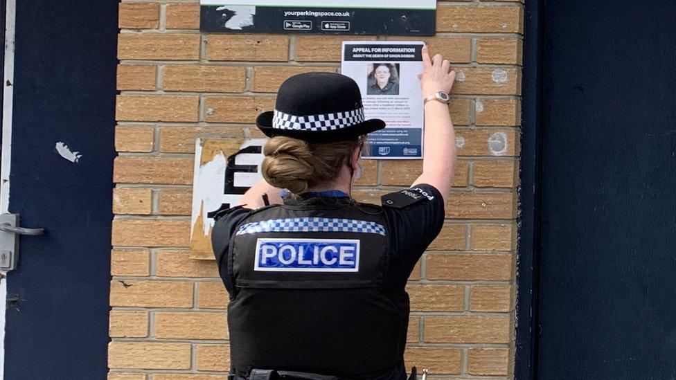 Officer putting up poster at ground